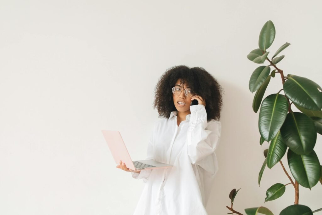 A Woman Holding a Laptop While on a Phone Call